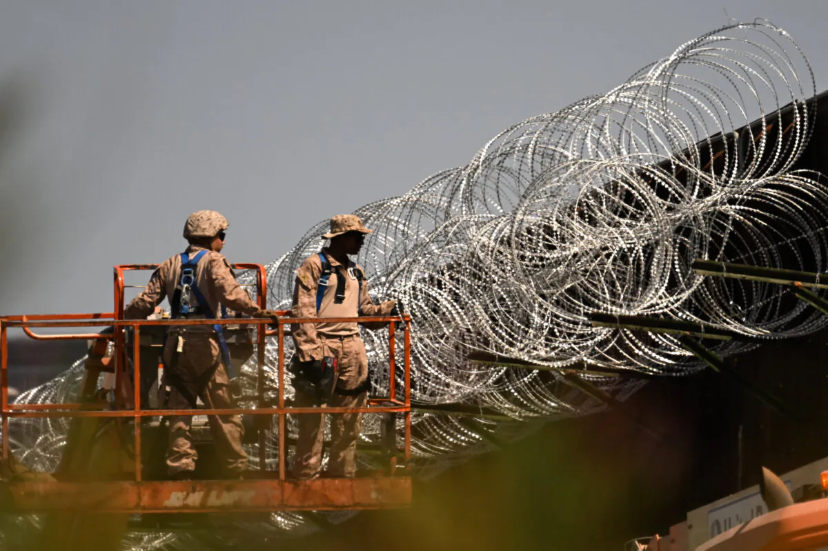 U.S. military personnel install concertina wire on top of the wall along the U.S.-Mexico border between San Diego and Tijuana near the San Ysidro Port of Entry in San Diego, Calif., on April 23, 2025. (Patrick T. Fallon/AFP/Getty Images)