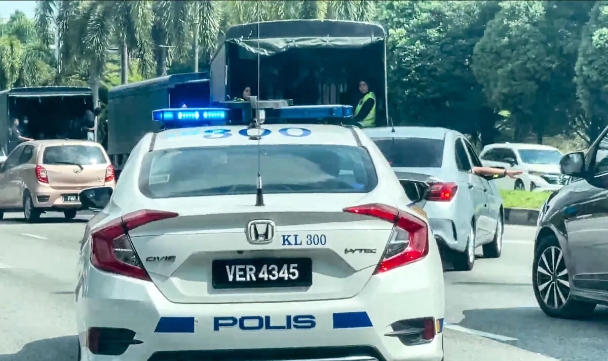 Malaysian police cars escort vans holding Falun Gong practitioners, in Kuala Lumpur, Malaysia, on April 13, 2025. (The Epoch Times)