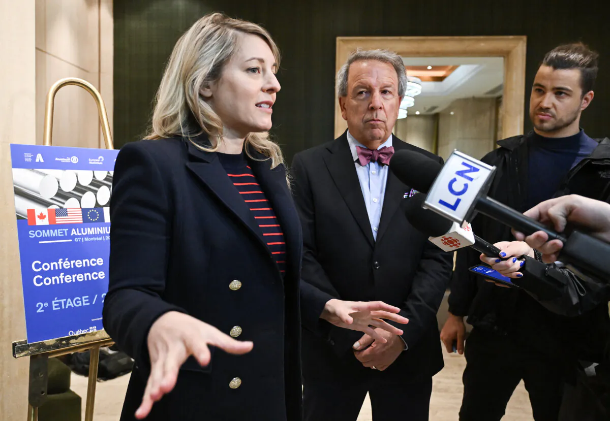 Jean Simard, president and CEO of the Aluminium Association of Canada, centre, looks on as Industry Minister Mélanie Joly speaks to the media after arriving for a meeting in Montreal on June 1, 2025. (The Canadian Press/Graham Hughes)