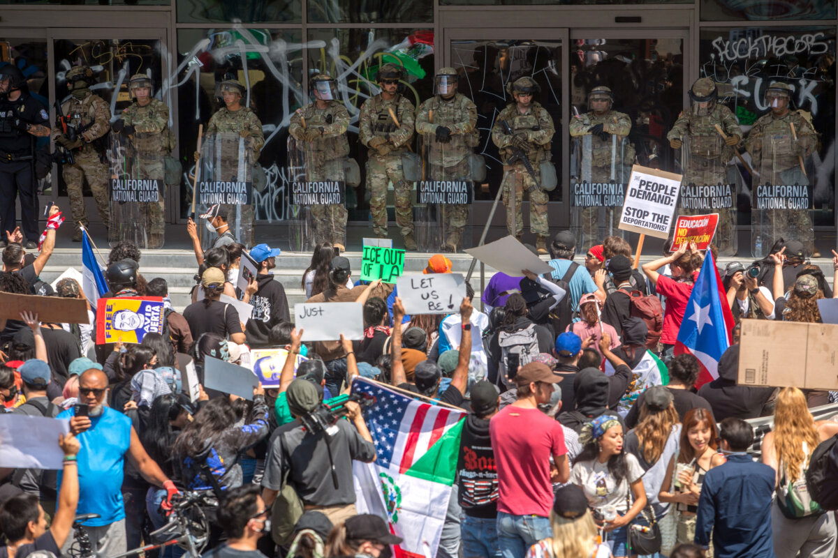 Demonstrators holding signs and flags face California National Guard members standing guard outside the Federal Building as they protest in response to federal immigration operations in Los Angeles, on June 9, 2025. (Apu Gomes/AFP via Getty Images)