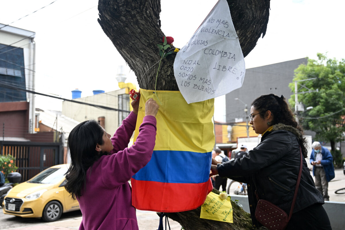 Women hold a Colombian flag in the place where Colombian Sen. Miguel Uribe Turbay was shot and wounded in a political event on June 7, in Bogota on June 9, 2025. (Raul ARBOLEDA/AFP)