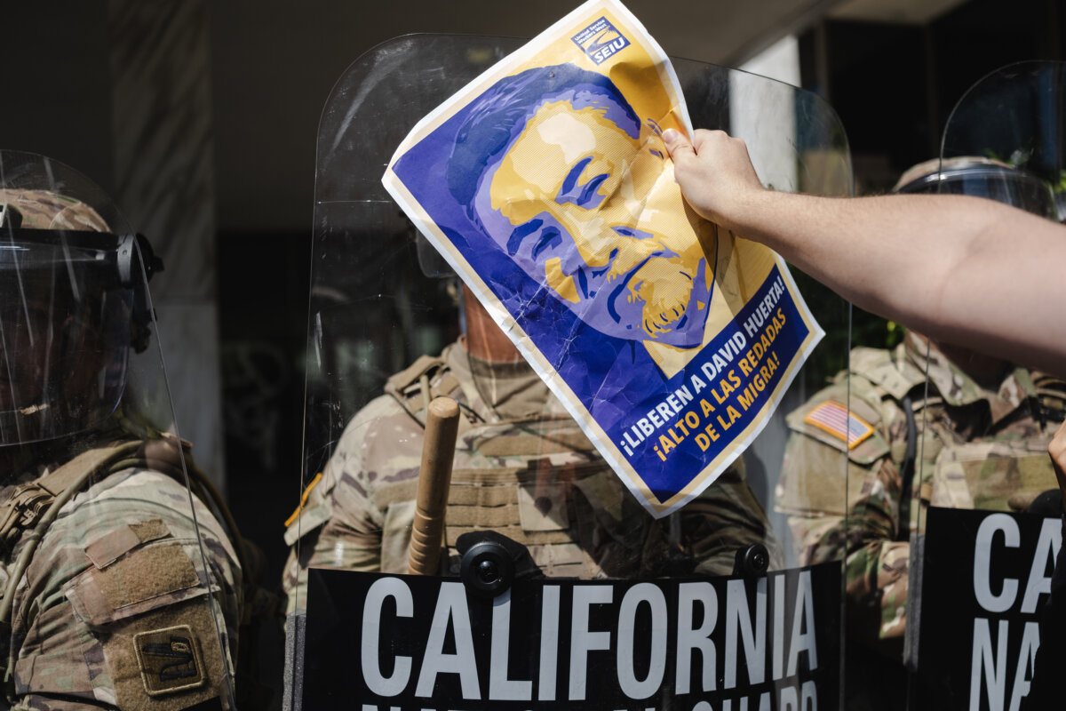 A protester holds a sign in support of SEIU President David Huerta in front of a National Guardsmen at the Robert Young Federal Building in Downtown Los Angeles on June 9, 2025. (Jim Vondruska/Getty Images)