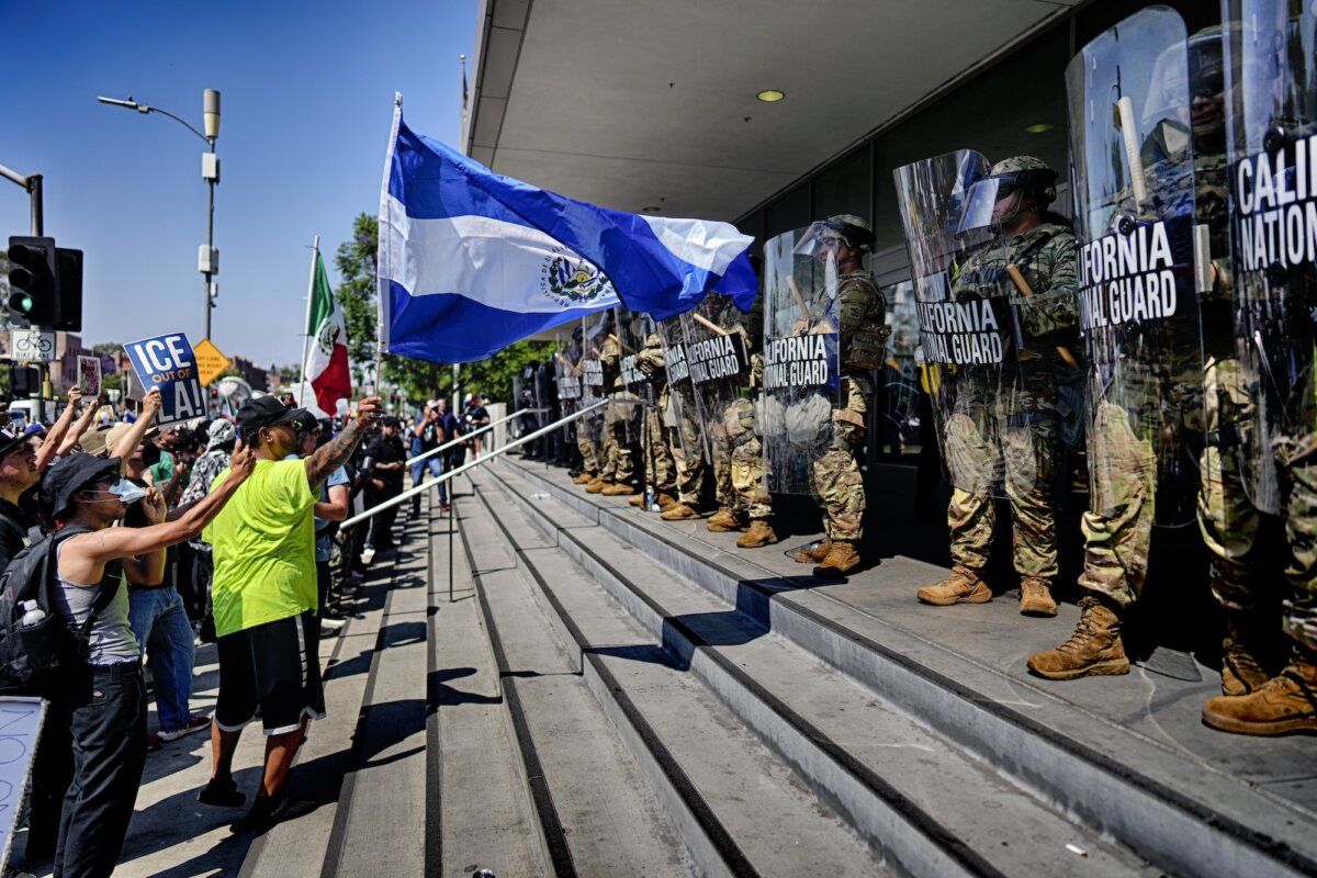 A protester waves the national flag of El Salvador in front of a line of California National Guard in front of Federal Building on Monday, June 9, 2025, in downtown Los Angeles. (AP Photo/Eric Thayer)
