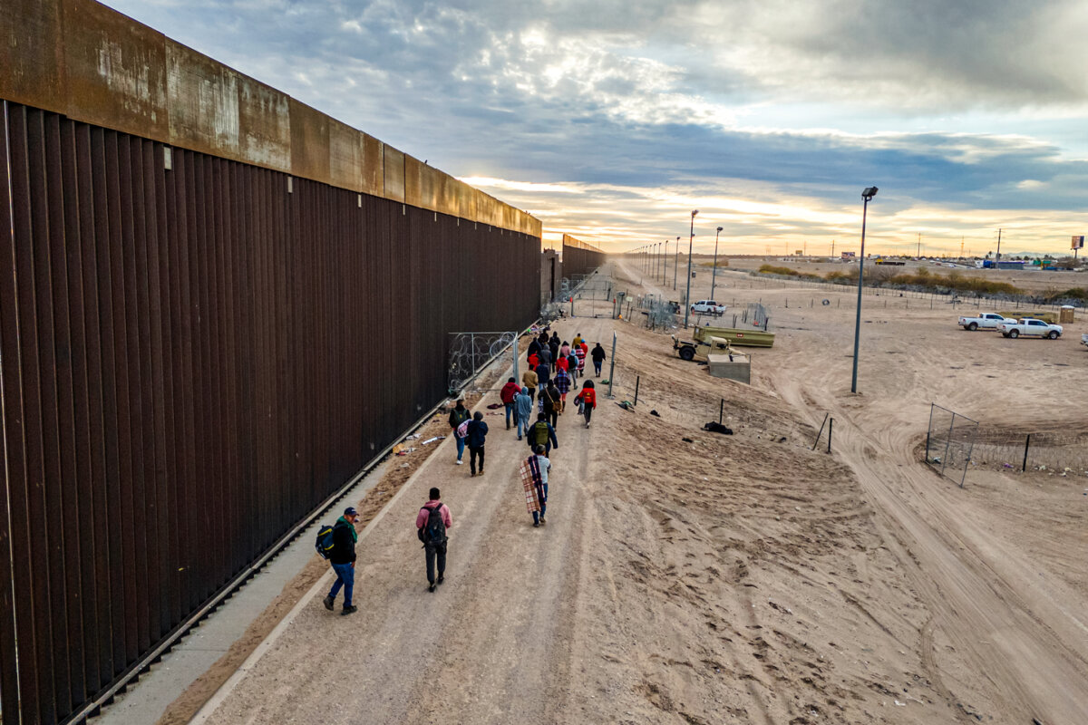 Illegal immigrants walk along the U.S.–Mexico border wall after crossing the Rio Grande into El Paso, Texas, on Feb. 1, 2024. (John Moore/Getty Images)