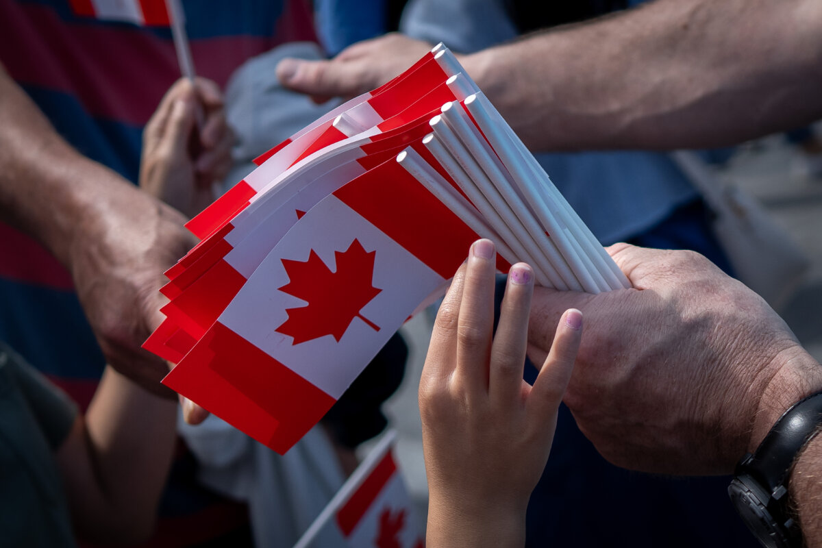 A boy reaches for a Canadian flag on Canada Day in Vancouver on July 1, 2024. (The Canadian Press/Ethan Cairns)