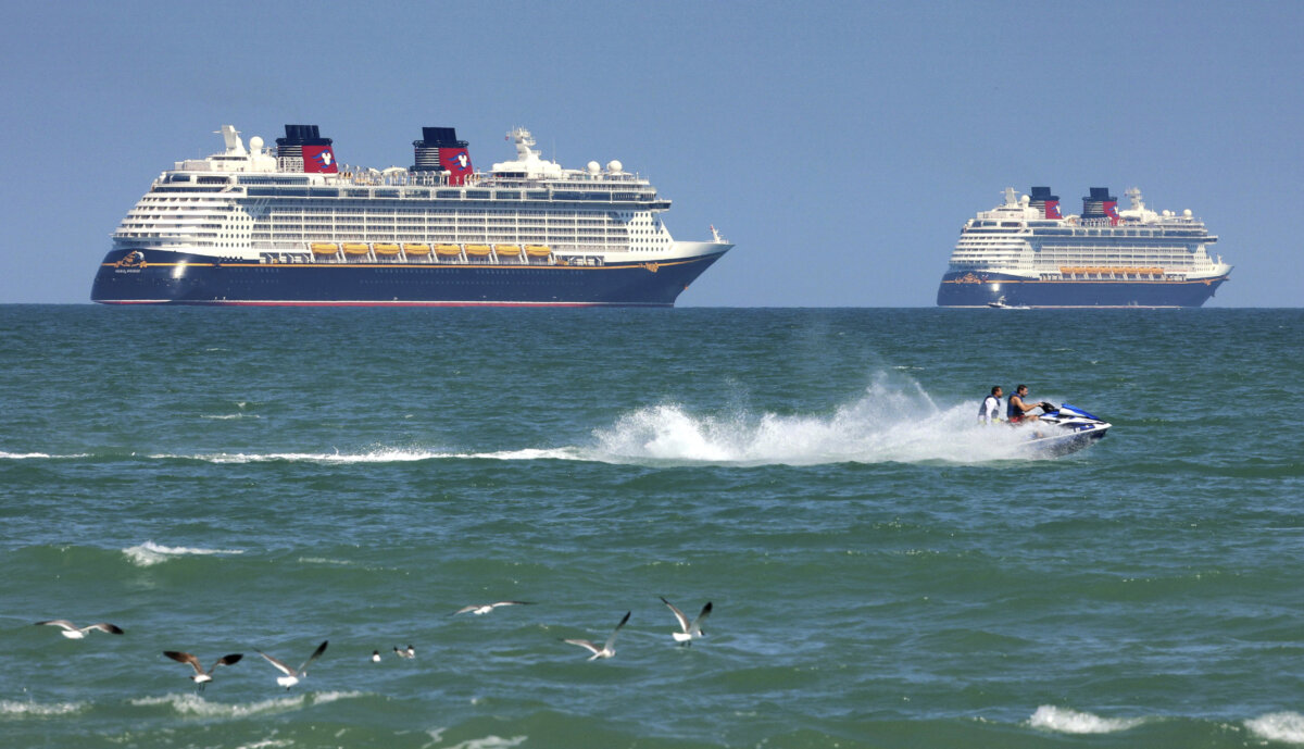 Jet skiers pass the Disney Cruise Line ships "Fantasy" (L) and "Dream" on the horizon as they sit stationary off of Cocoa Beach, Fla., in this view from Lori Wilson Park, on March 24, 2021. (Joe Burbank/Orlando Sentinel via AP)
