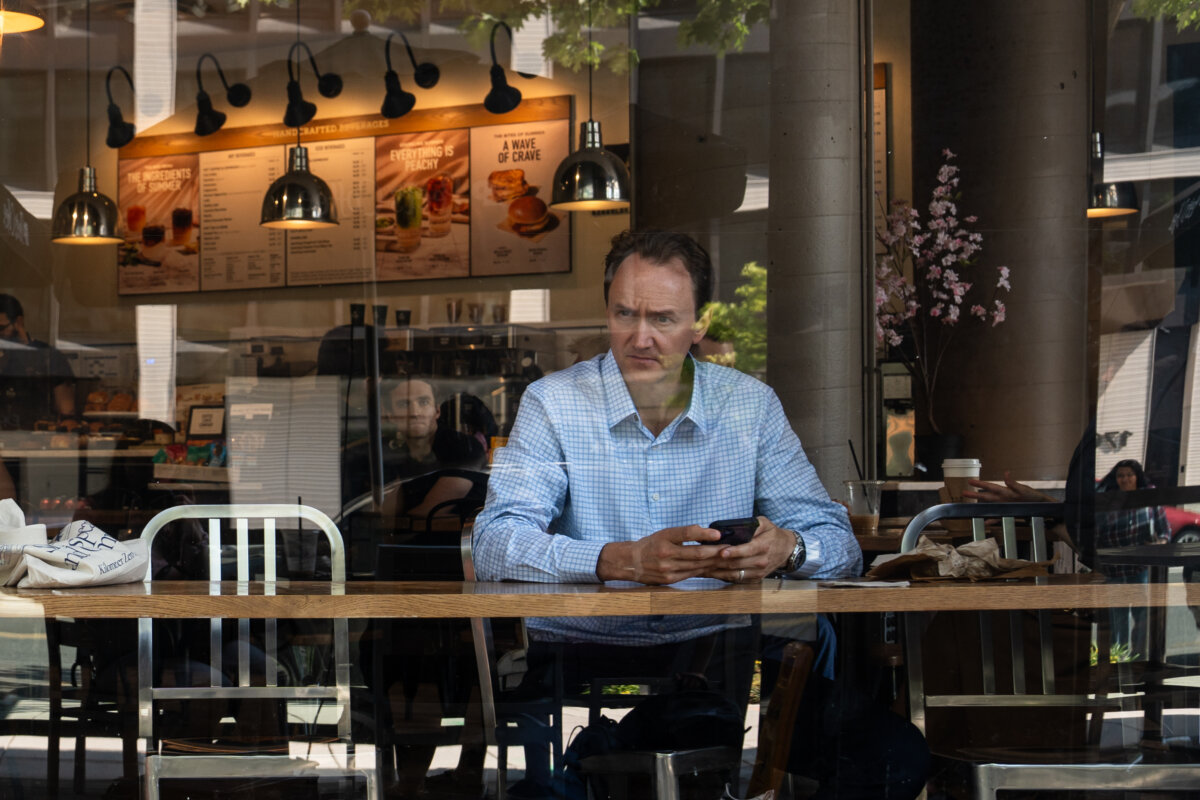 A man looks out the window at a coffee shop in Washington, on July 1, 2025. (Madalina Kilroy/The Epoch Times)