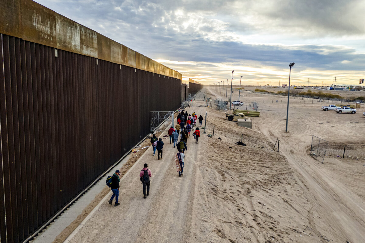 Illegal immigrants walk alongside the U.S.–Mexico border wall after crossing the Rio Grande into El Paso, Texas, on Feb. 1, 2024. (John Moore/Getty Images)