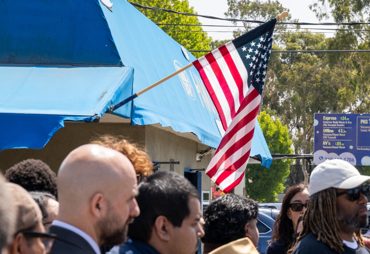 An American flag waves above immigration activists in Torrance, Calif., on July 2, 2025. (John Fredricks/The Epoch Times)
