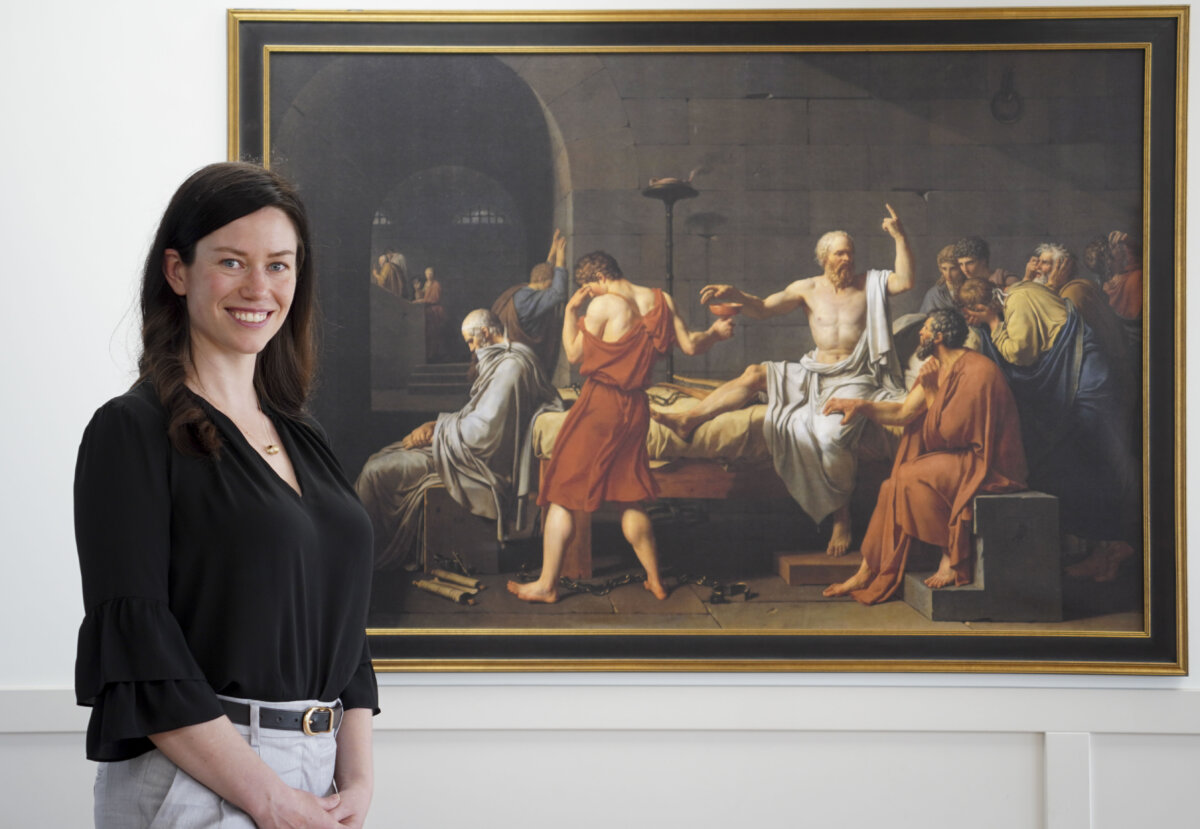 Caylan Ford, founder of the Alberta Classical Academy, stands beside a replica of The Death of Socrates painting at the Calgary Currie campus on June 6, 2025. (Carolina Avendano/The Epoch Times)