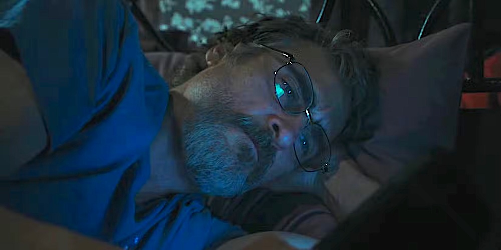 man with blue shirt and glasses on bed in Eddington