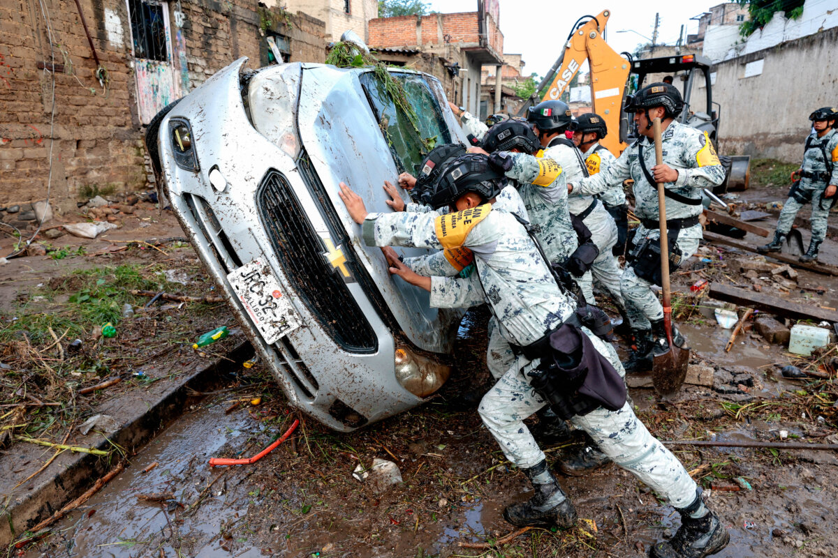 Army soldiers turn over a damaged car affected by flash flooding due to heavy rains in Zapopan, Jalisco state, Mexico, on July 16, 2025. At least one child died and dozens of homes and streets were flooded after heavy rains hit the region in western Mexico on July 15. (Ulises Ruiz/AFP via Getty Images)