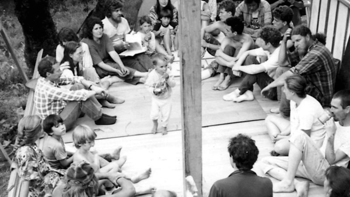 a group of people sit wooden floor in Commune