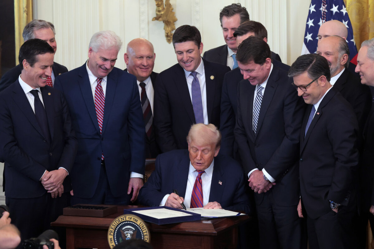 U.S. President Donald Trump, surrounded by lawmakers, signs the GENIUS Act into law during a ceremony in the East Room of the White House in Washington on July 18, 2025. (Anna Moneymaker/Getty Images)