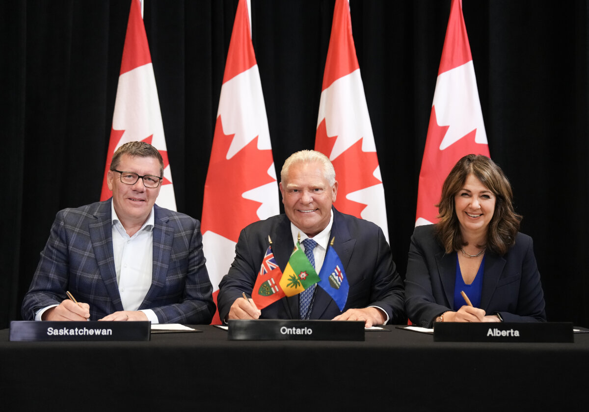 (L-R) Saskatchewan Premier Scott Moe, Ontario Premier Doug Ford, and Alberta Premier Danielle Smith sign a memorandum of understanding during the 2025 summer meetings of Canada's Premiers at Deerhurst Resort in Huntsville, Ont., on July 22, 2025. (The Canadian Press/Nathan Denette)