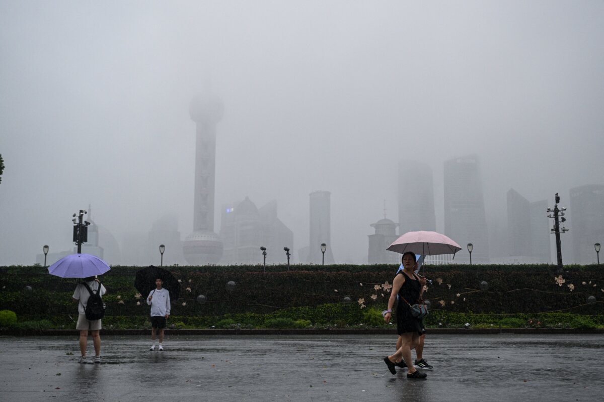 People walk on The Bund promenade along the Huangpu River during the passage of Typhoon Co-may in Shanghai on July 30, 2025. (Hector Retamal/AFP via Getty Images)