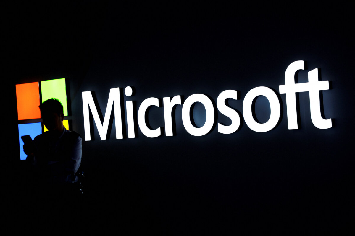 A man looks at his phone in front of the Microsoft logo during the 2025 Mobile World Congress in Barcelona on March 3, 2025. (Albert Gea/Reuters)