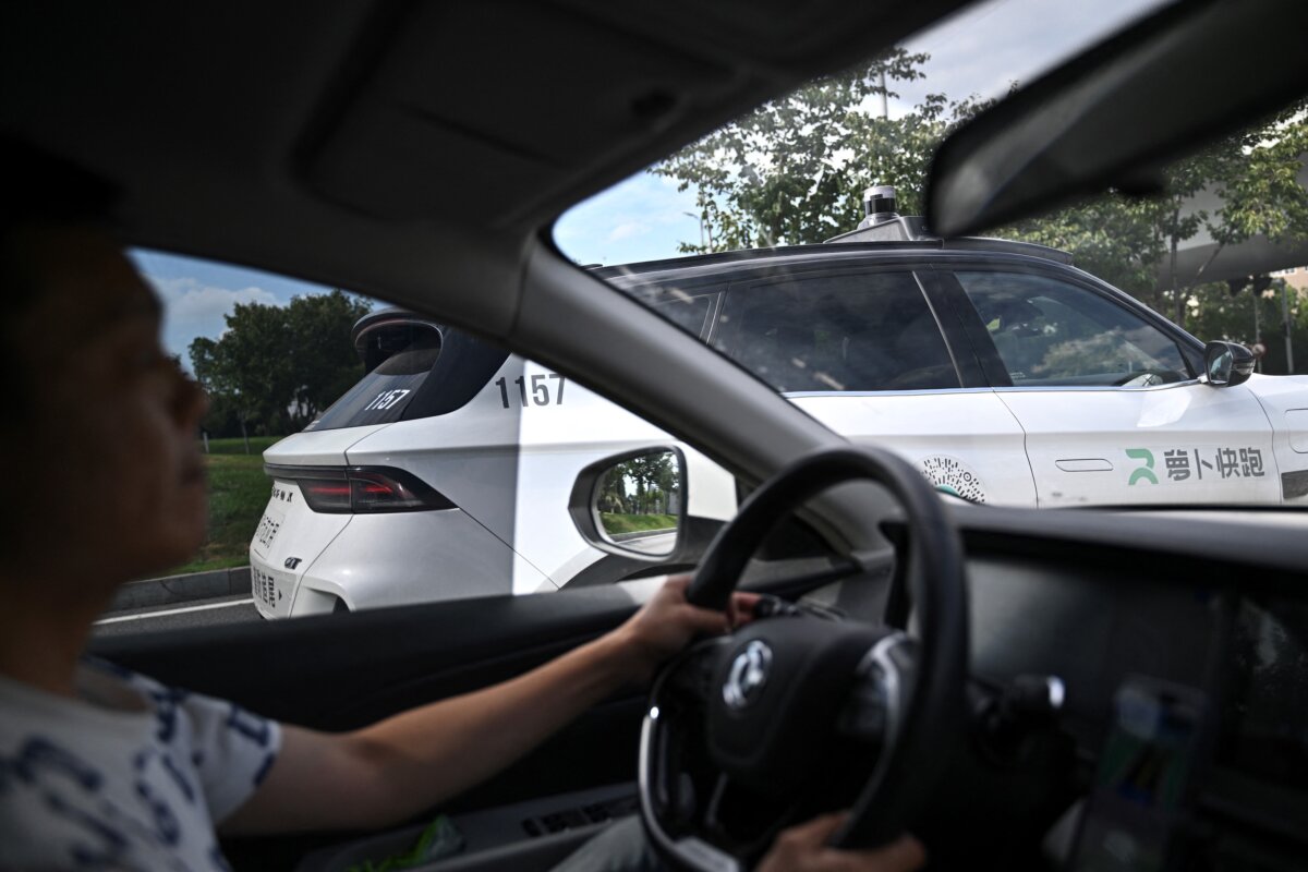 A taxi driver operating his car on a road alongside a self-driving robotaxi developed as part of tech giant Baidu's Apollo Go self-driving project, in Wuhan, in central China's Hubei province on Aug. 2, 2024. (Pedro Pardo/AFP via Getty Images)