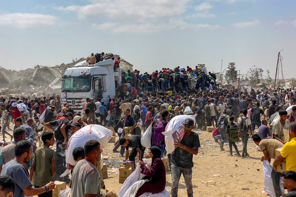 Displaced Gaza residents carry food parcels as they raid trucks carrying humanitarian aid in Khan Yunis, in the southern Gaza Strip on Aug. 9, 2025. (AFP via Getty)