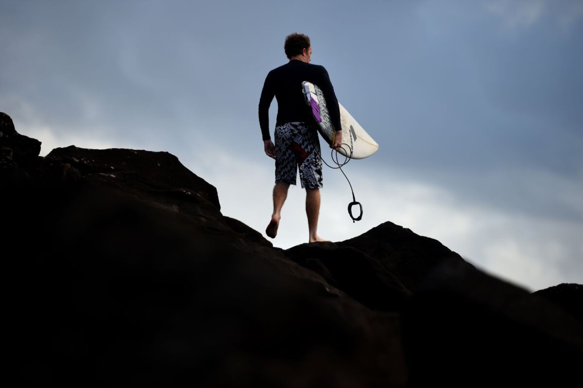 A surfer makes his way over rocks to surf at Boulders Beach in Ballina in northern New South Wales, Australia on April 29, 2016. (Peter Parks/AFP via Getty Images)