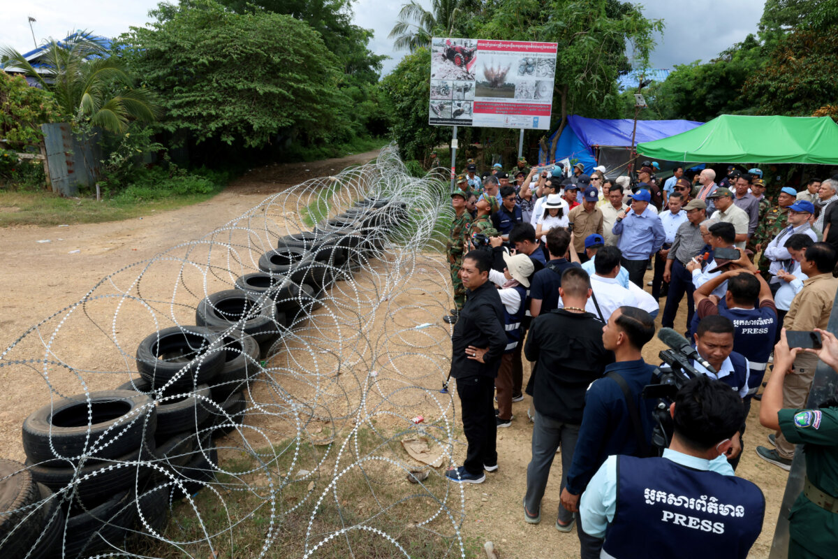 Foreign diplomats and representatives of international organisations, including UN agencies, looking at barbed wire and tyres that according to Cambodian officials was placed by the Thai military in a disputed area along the Cambodia-Thailand border in Banteay Meanchey province, on Aug. 22, 2025. (STR/AFP via Getty Images)