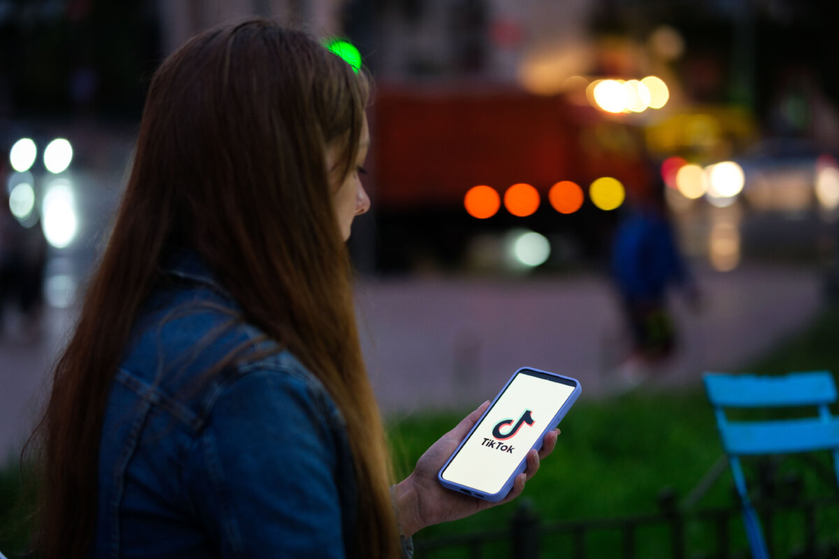 A woman holds a phone displaying the TikTok app, in this file photo, on Aug. 11, 2024. (Oleksii Pydsosonnii/The Epoch Times)