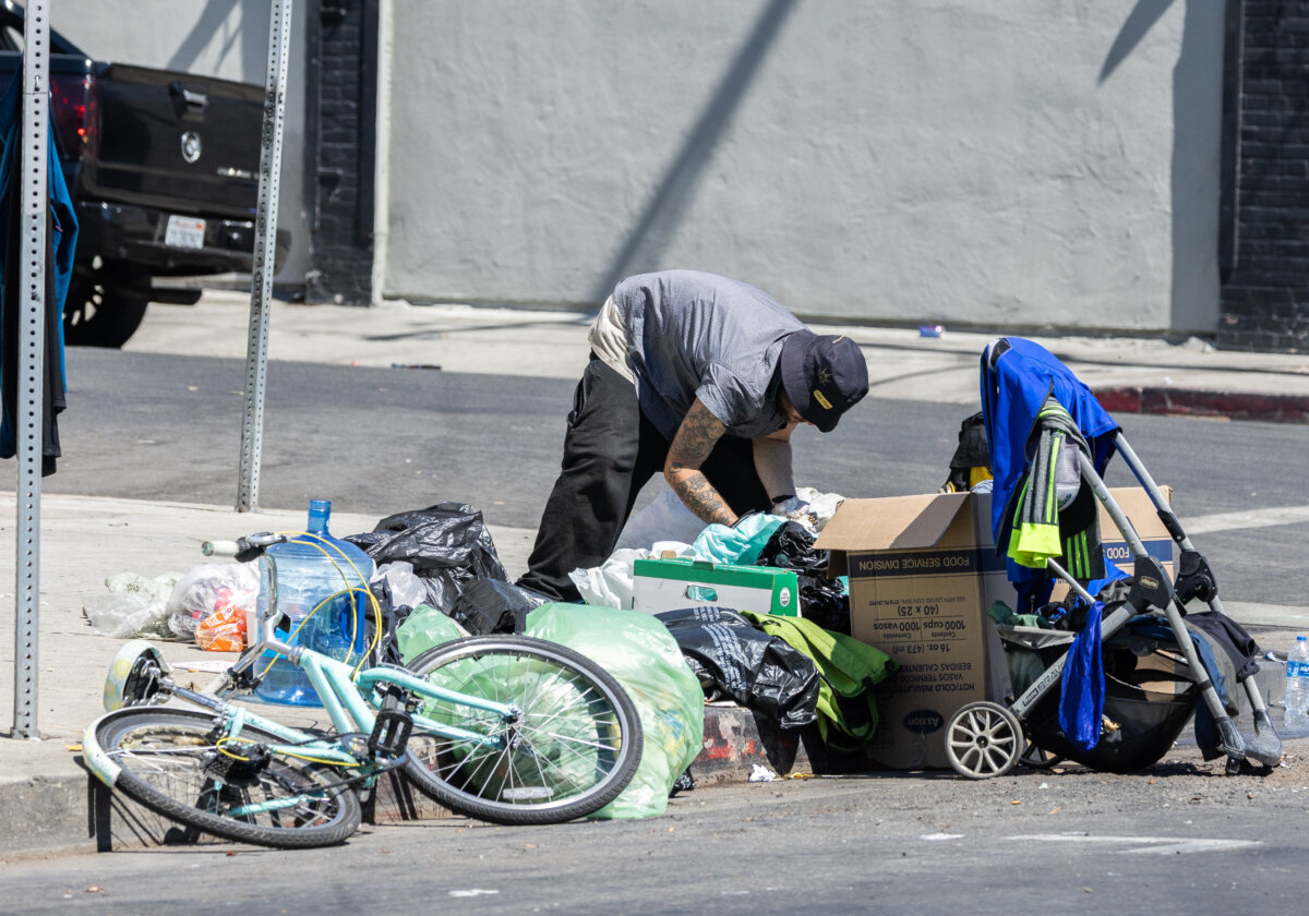 A homeless individual sorts through items on a sidewalk, in this file photo. (John Fredricks/The Epoch Times)