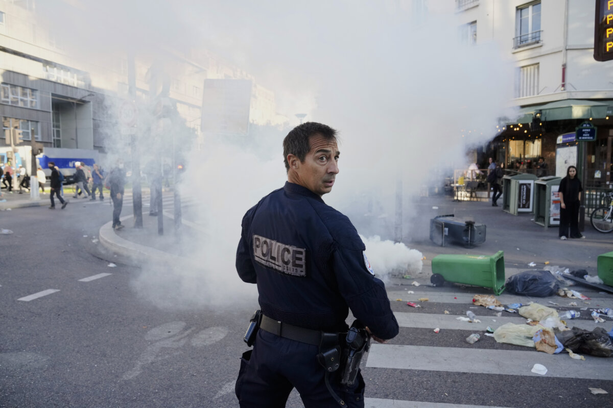 A police officer stands next to bins placed on a street to block it during the "Block Everything" protest movement in Paris, on Sept. 10, 2025. (Thibault Camus/AP Photo)