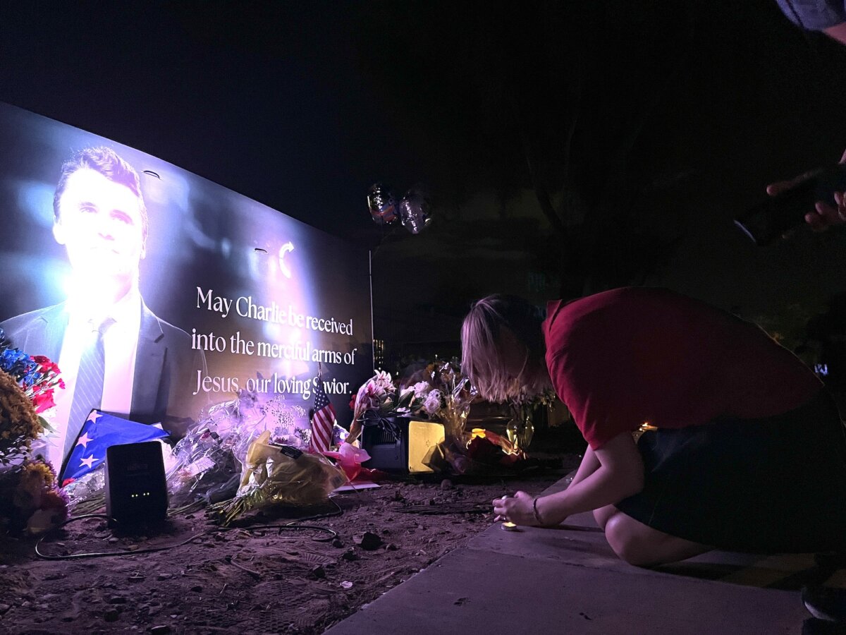 Katy, who lives in Phoenix and attends a private Catholic high school, lights a candle at the base of a shrine honoring slain conservative activist Charlie Kirk in Phoenix on Sept. 10, 2025. (Allan Stein/The Epoch Times)