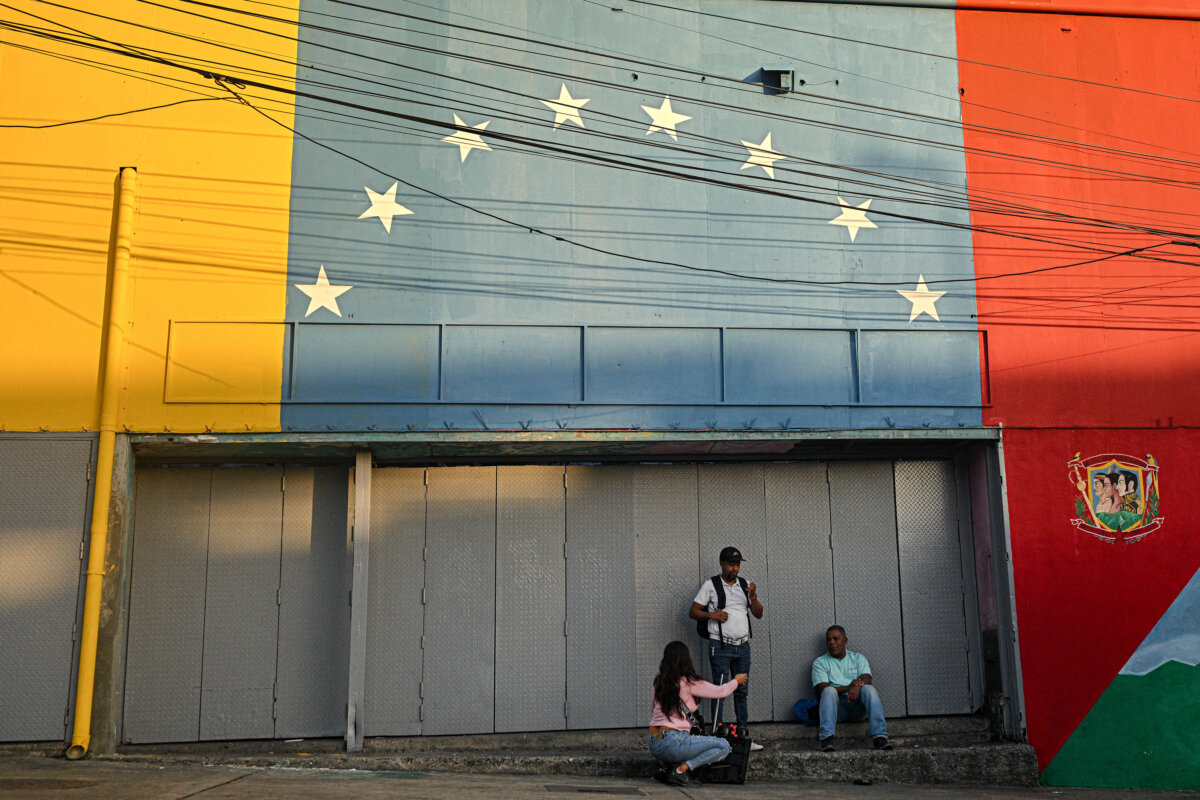 People talk in front of a mural with the colors of the Venezuelan national flag in Caracas, Venezuela, on Sept. 12, 2025. (Federico Parra/AFP via Getty Images)