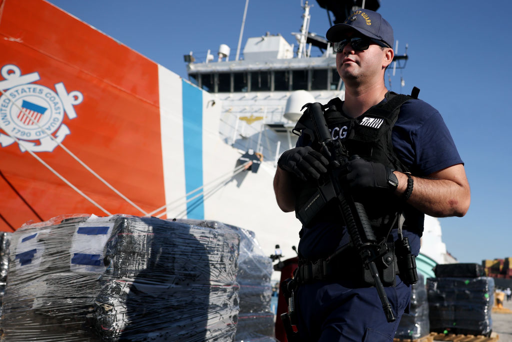 A U.S. Coast Guard crew member stands guard among wrapped packages of cocaine and marijuana offloaded from Coast Guard Cutter Stone at Port Everglades in Port Everglades, Fla., on March 20, 2025. (Joe Raedle/Getty Images)