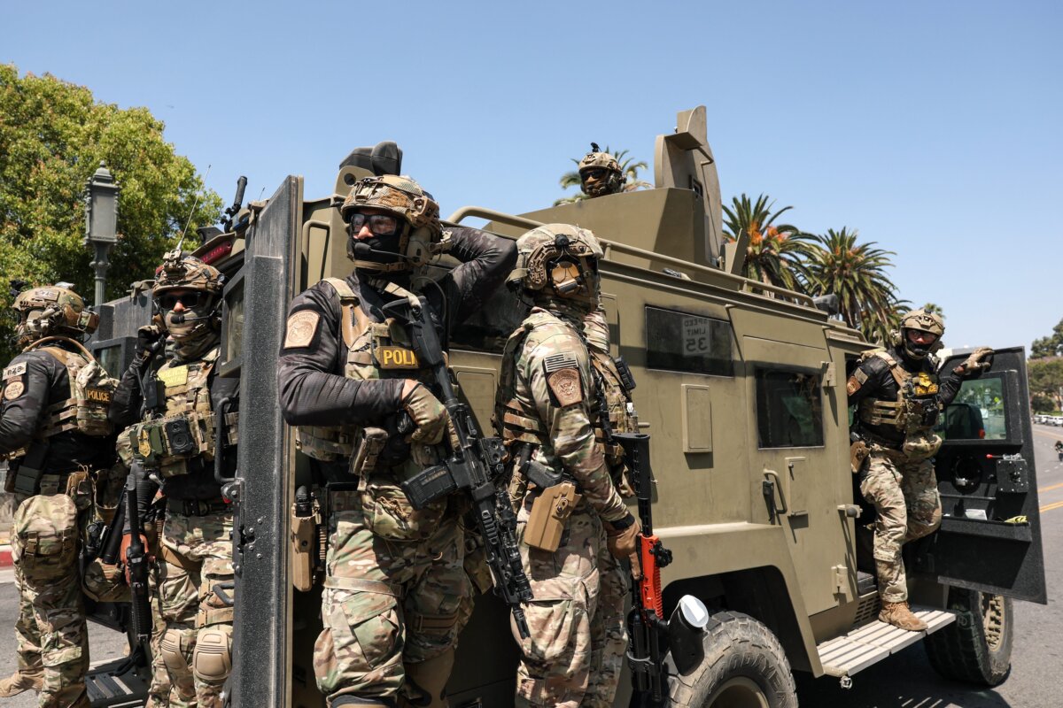 Federal agents with Customs and Border Patrol ride on an armored vehicle driving slowly down Wilshire Boulevard near MacArthur Park in Los Angeles on July 7, 2025. (Patrick T. Fallon/AFP via Getty Images)