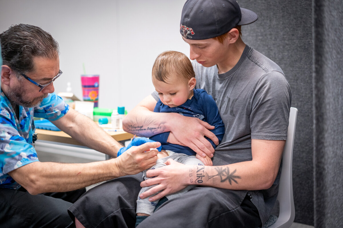 A man holds his 14-month-old son while he gets the MMR vaccine at a clinic in Lubbock, Texas, on March 1, 2025. (Jan Sonnenmair/Getty Images)