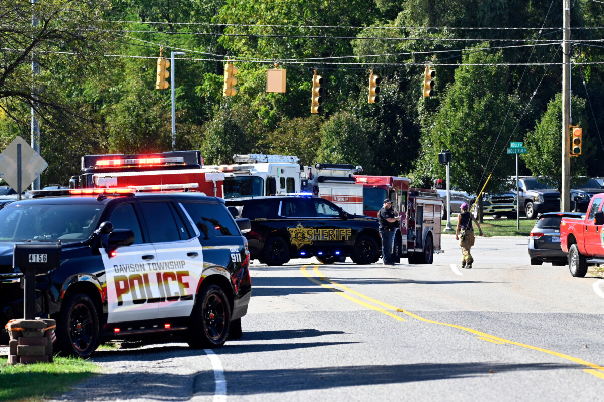 Law enforcement and fire personnel stand near the corner of McCandlish and Holly road, near a shooting that took place at The Church of Jesus Christ of Latter-day Saints in Grand Blanc, Mich., on Sept. 28, 2025. (Jose Juarez/AP Photo)
