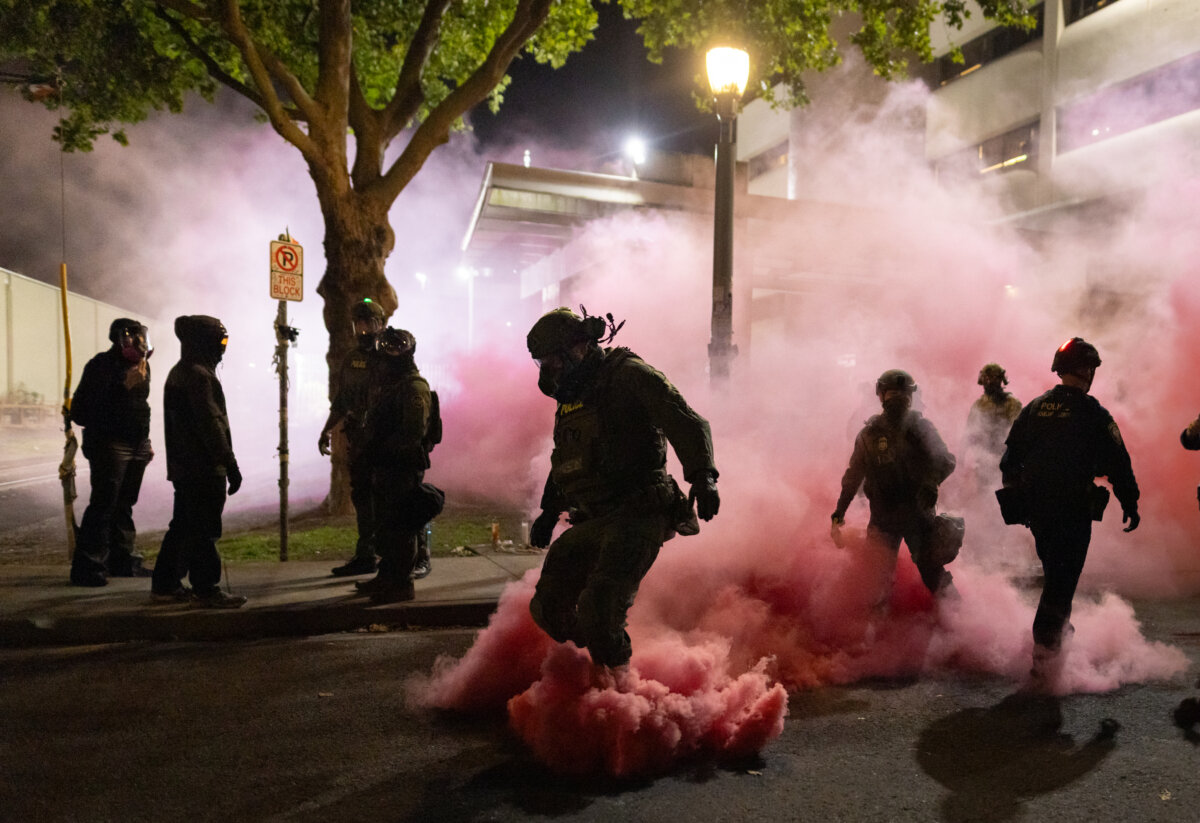 Federal officers deploy smoke grenades to deter protestors in front of Immigration and Customs Enforcement offices in Portland, Oregon, on Oct. 5, 2025. (John Fredricks/The Epoch Times)