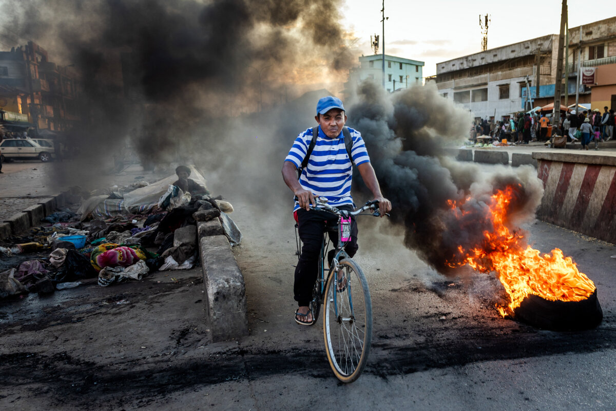 A cycllist rides past a burning tire during clashes between protesters and Malagasy security forces at a demonstration demanding the resignation of President Andry Rajoelina in Antananarivo, Madagascar, on Oct. 6, 2025. (Luis Tato/AFP via Getty Images)