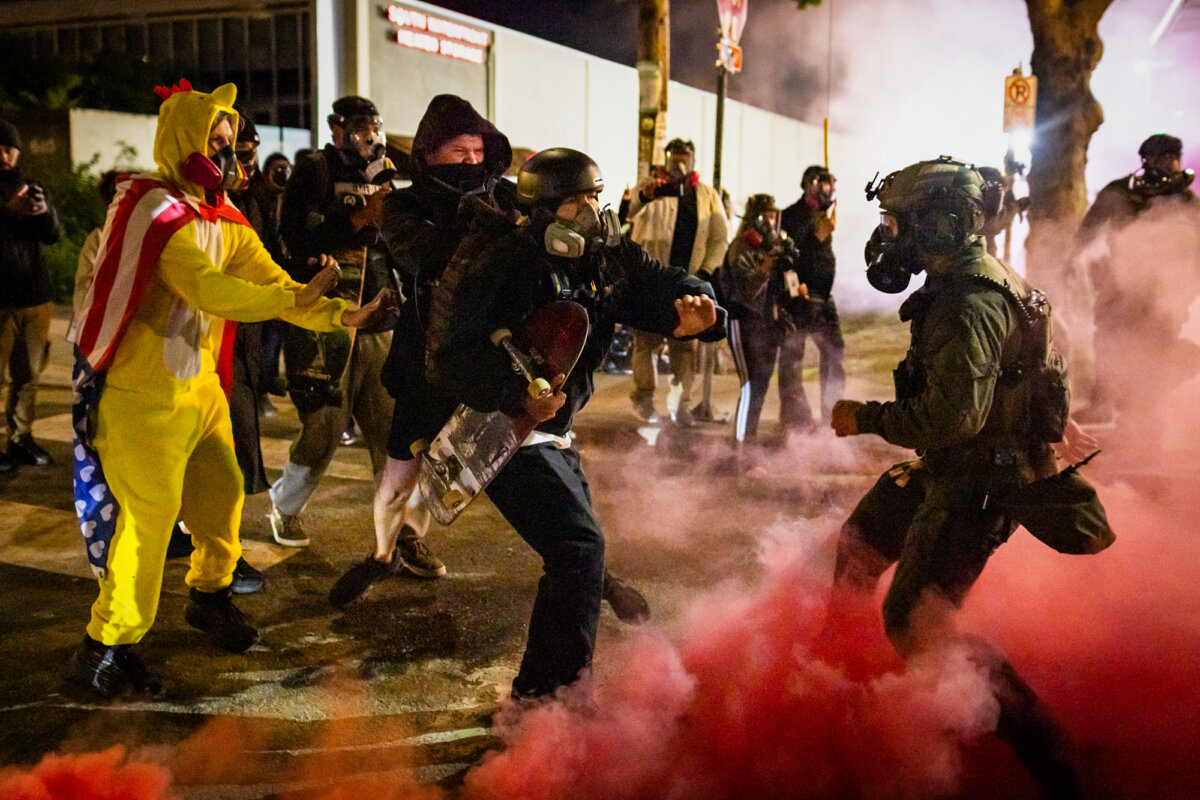 An Antifa member kicks back a smoke bomb deployed by federal officers in front of Immigration and Customs Enforcement offices in Portland, Ore., on Oct. 5, 2025. (John Fredricks/The Epoch Times)