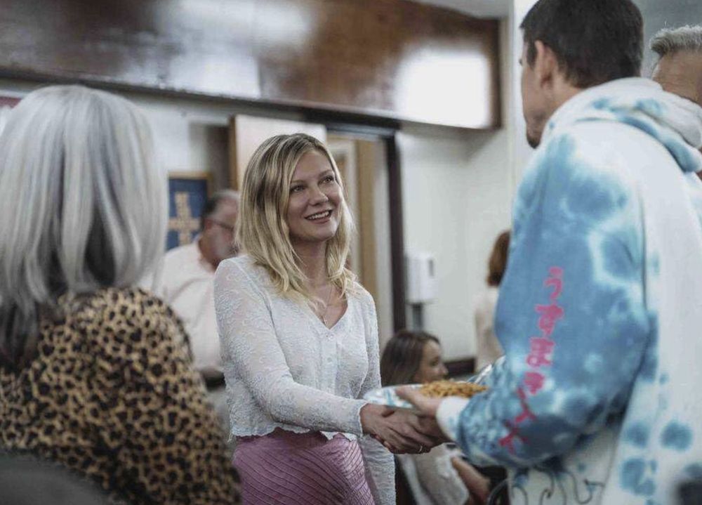 woman in pink skirt and man in blue hoodie shake hands in Roofman