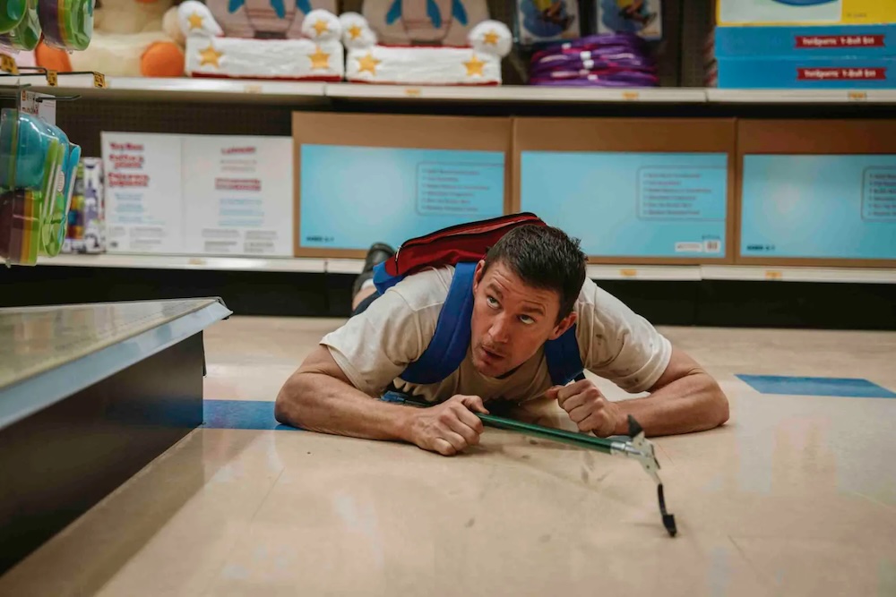 man with backpack crawls on a store floor in Roofman