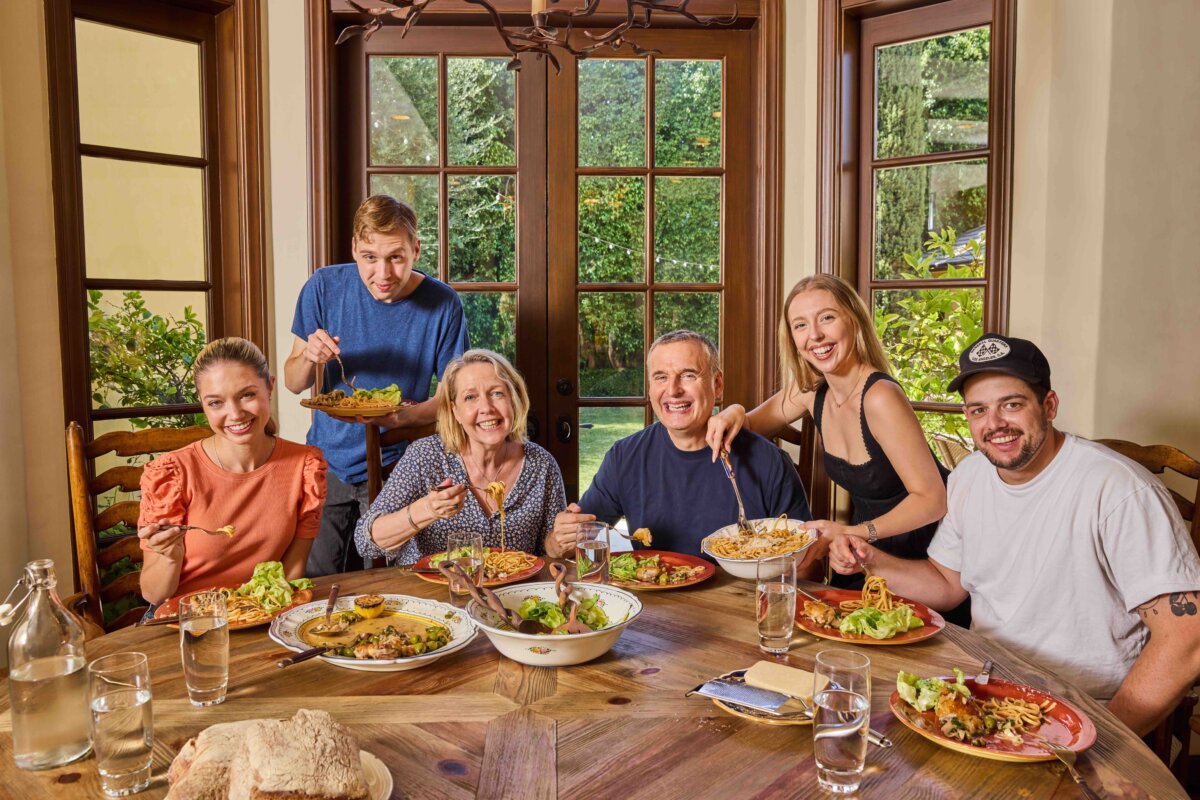 Phil Rosenthal (C), the star and creator of the series “Somebody Feed Phil,” shares a meal with family. (Andrea D’Agosto)