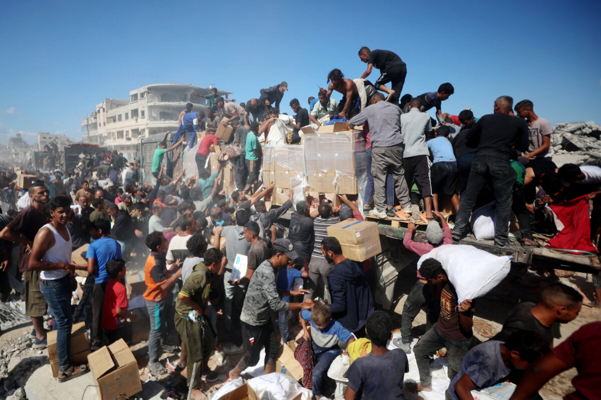 Palestinians collect aid parcels from aid trucks that entered from the Karem Abu Salem crossing, in Khan Yunis in the southern Gaza Strip on Oct. 12, 2025. (Omar Al-Qattaa/AFP)