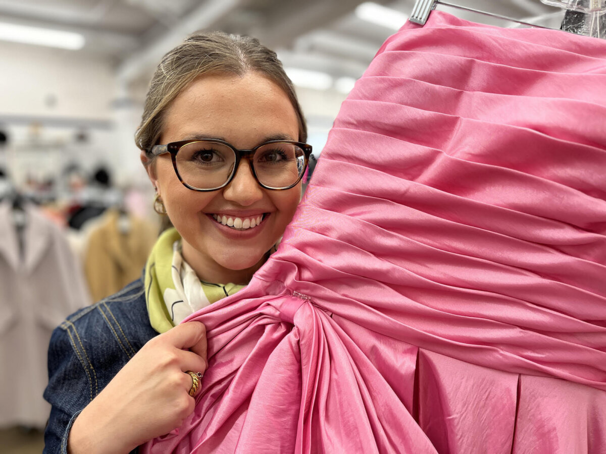 Sonni Hood, Unclaimed Baggage's senior public relations manager, shows a pink satin prom dress inside the massive retail store in Scottsboro, Ala., on Oct. 8, 2025. (Allan Stein/The Epoch Times)