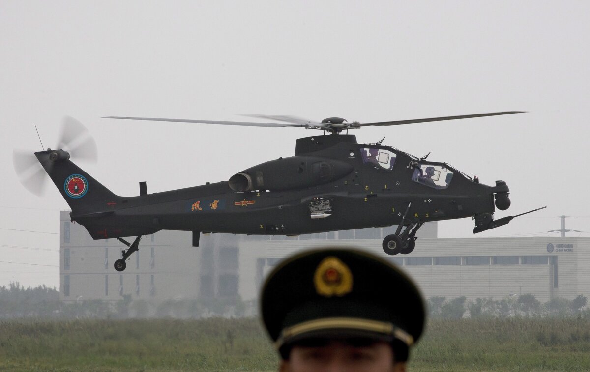 A Chinese Army Z-10WZ attack helicopter flies as a paramilitary policeman stands guard during a demonstration at the 2nd China Helicopter Exposition in Tianjin, China, on Sept. 5, 2013. (AP Photo/Andy Wong)