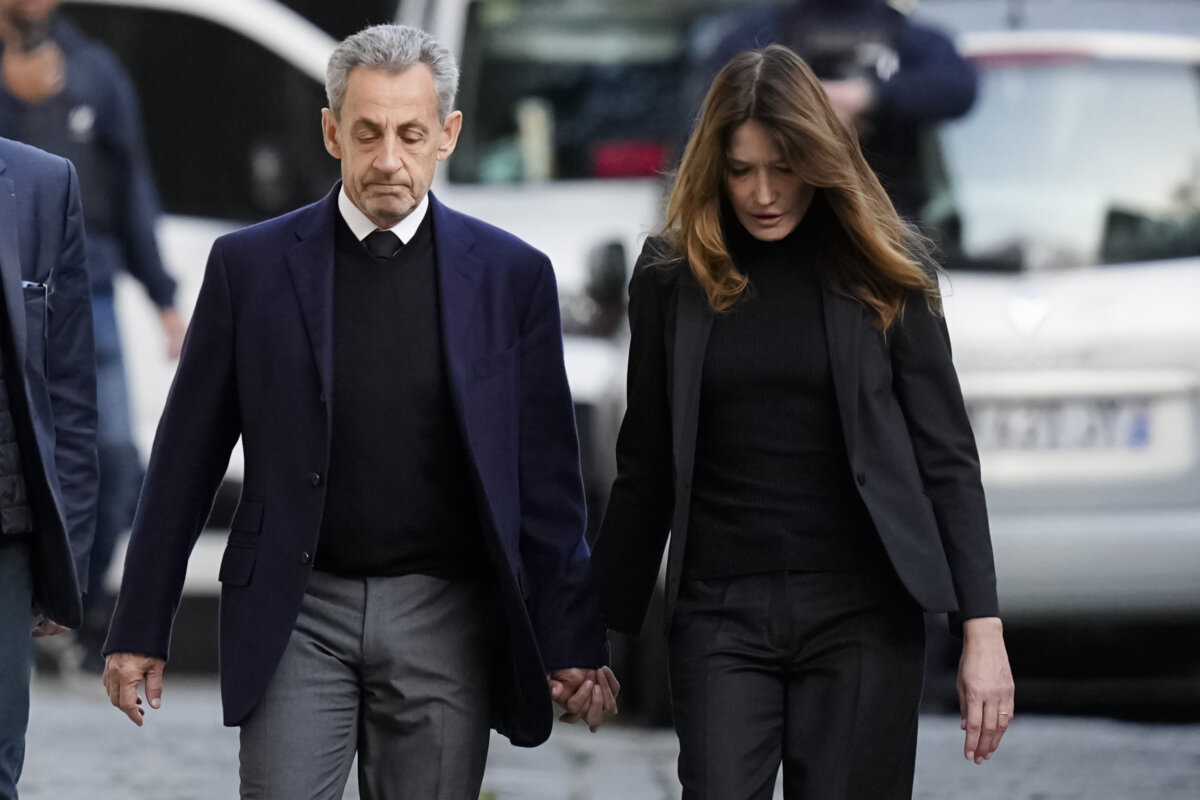 Former French President Nicolas Sarkozy and his wife Carla Bruni-Sarkozy leave their home Tuesday, Oct. 21, 2025 in Paris as Nicolas Sarkozy heads to prison to serve time for a criminal conspiracy to finance his 2007 election campaign with funds from Libya. (AP Photo/Thibault Camus)