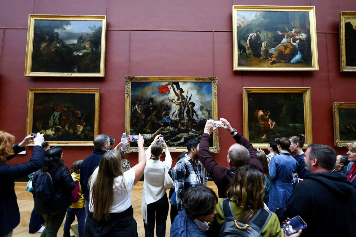 Visitors take pictures of "La Liberte guidant le peuple" (Liberty Leading the People, 1830) by French artist Eugene Delacroix (1798–1863) displayed in the Louvre Museum on the day it reopened to the public after last Sunday's heist, The Galerie d'Apollon where eight pieces of Napoleon and the Empress's jewelry collection were stolen remains closed, in Paris, France, on Oct. 22, 2025. (Gonzalo Fuentes/Reuters)