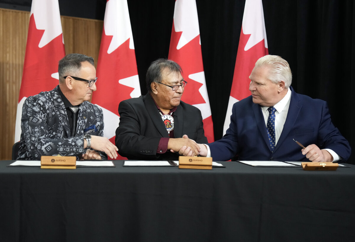Ontario Premier Doug Ford, right, signs an agreement with Webequie First Nation Chief Cornelius Wabasse, centre, and Greg Rickford, Indigenous Affairs Minister at Queen's Park in Toronto on Oct. 29, 2025. The northern Ontario First Nation has signed a partnership deal with the province designed to speed up construction of a road to the mineral-rich Ring of Fire. (The Canadian Press/Nathan Denette)