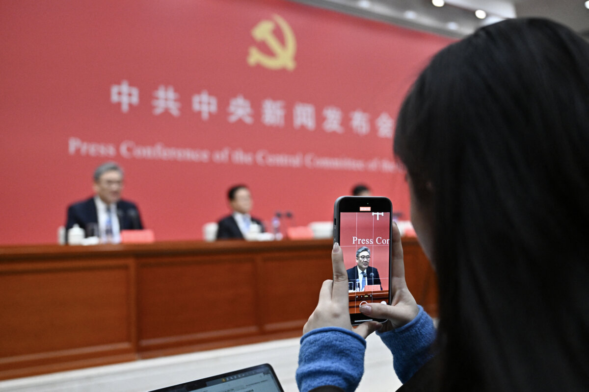 A journalist records a video of Chinese Minister of Commerce Wang Wentao as he attends a press conference of the Central Committee of the Chinese Communist Party in Beijing on Oct. 24, 2025. (Pedro Pardo/AFP/Getty Images)