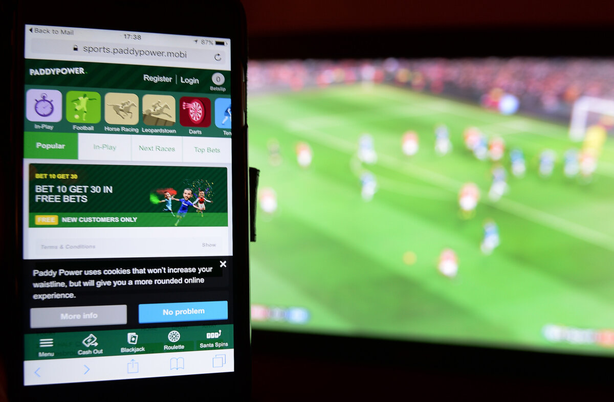 A smartphone user accesses the Paddy Power gambling website while watching a sporting event on television. (John Stillwell/PA)