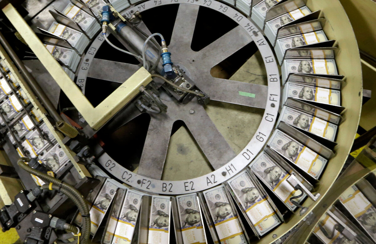 In this Sept. 24, 2013 file photo, freshly cut stacks of $100 bills make their way down the line at the Bureau of Engraving and Printing Western Currency Facility in Fort Worth, Texas. (LM Otero/AP)
