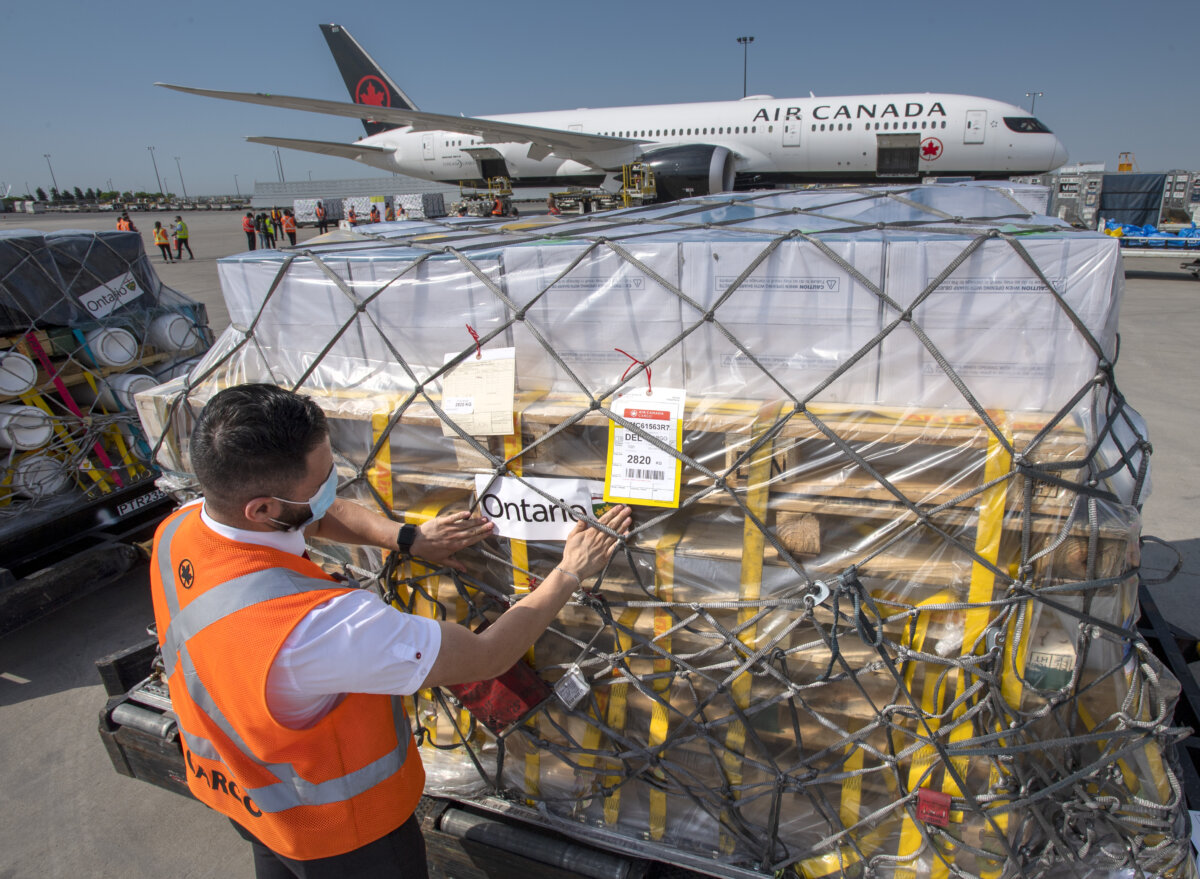 A worker puts an Ontario sticker on a load of hundreds of ventilators as they are loaded on to an airplane destined for India in Toronto on May 18, 2021. (The Canadian Press/Frank Gunn)